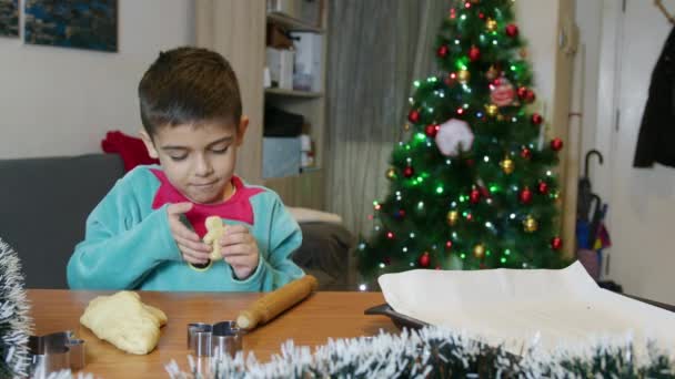 Carino elfo ragazzo che fa biscotti uomo pan di zenzero davanti all'albero di Natale. Al rallentatore. Filmati 4k di alta qualità - Filmati, video