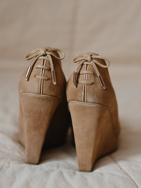 Vertical close up shot of Women's beige shoes on a solid high platform made of genuine leather (suede). There are lace bows on the back. View from the back. - Photo, Image