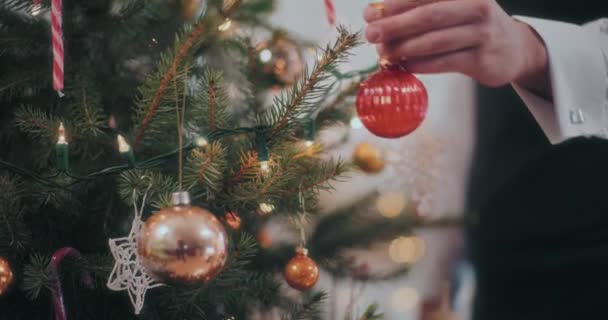 Oříznuté mužské ruce visí červená cetka na vánoční stromeček doma - Záběry, video