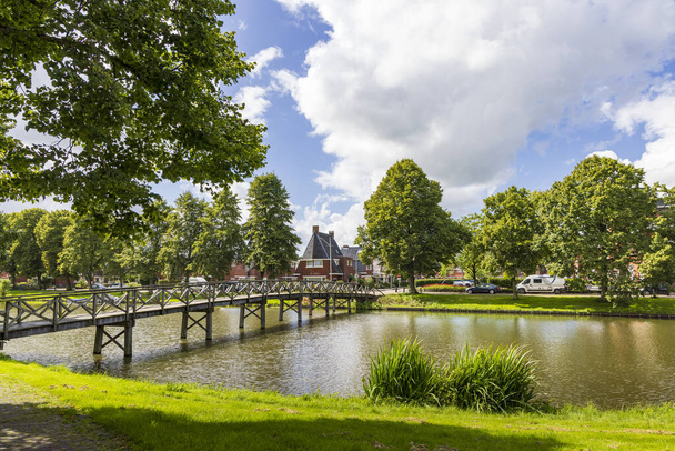 オランダのデルフェルデンリル(2023年8月8日):オランダのグローニンゲン州のヴィッテンシンゲル道路に橋を渡る池を持つデルフェルデンリの街並み - 写真・画像