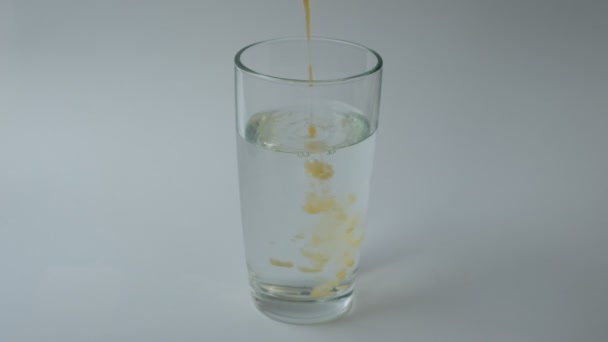 Mezcla de suplementos dietéticos y vitaminas en un vaso de agua.  - Metraje, vídeo