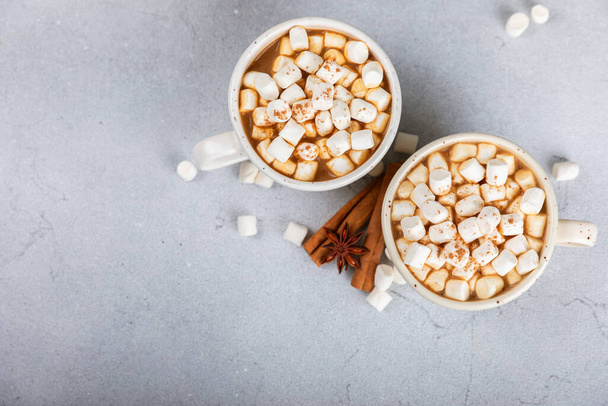 Hot drink with marshmallows and candy cane in cup on texture table.Cozy seasonal holidays.Hot cocoa with gingerbread Christmas cookies.Hot chocolate with marshmallow and spices.Copy space. - Photo, Image
