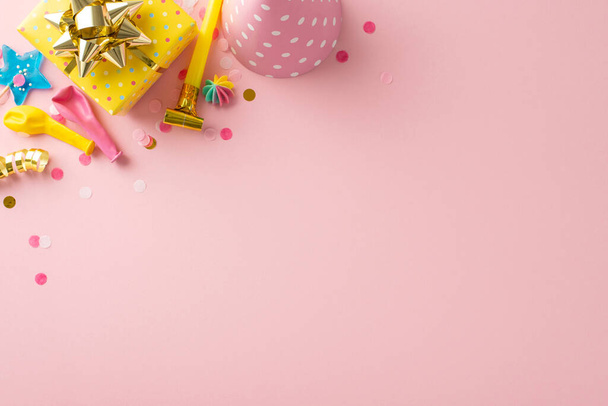 Dulce idea de exhibición de cumpleaños. Vista superior de la mesa festiva con una decoración encantadora, caramelos, regalo envuelto, sombrero de celebración, pipa, globos, confeti, serpentina sobre fondo rosa pálido. Espacio amigable con texto - Foto, imagen