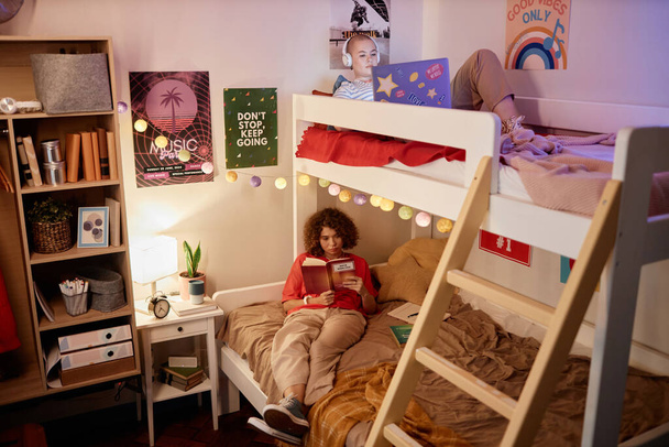 Портрет двух студенток колледжа, наслаждающихся расслабляющим вечером на двухъярусной кровати в комнате общежития, пространство для копирования - Фото, изображение