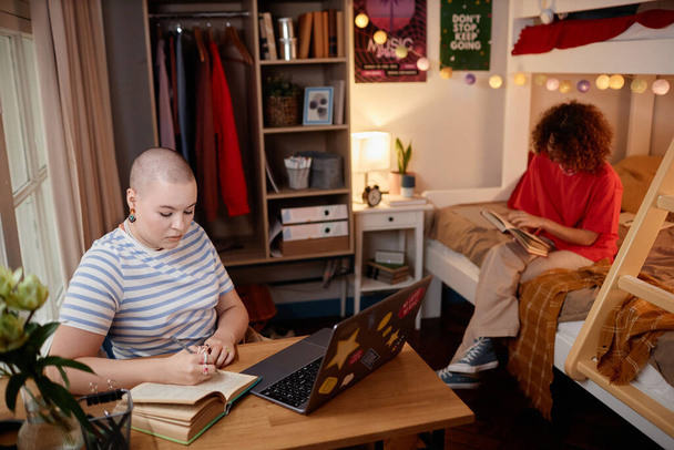 Portrait of two young women studying and doing homework in college dorm room, copy space - Photo, Image