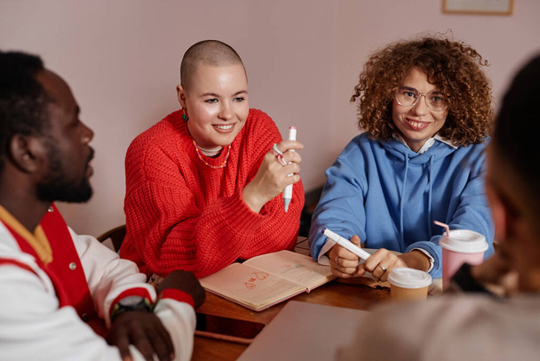 Groupe multiethnique de jeunes étudiants assis à table dans un dortoir universitaire ensemble et partageant des idées - Photo, image