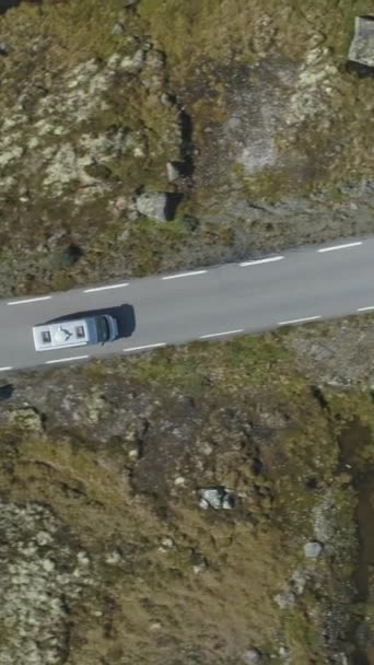 White Motorhome Car ist auf der Bergstraße in Norwegen am Summer Sunny Day unterwegs. Vertikale Luftaufnahme von oben nach unten. Drohne fliegt seitlich. Vertikales Video - Filmmaterial, Video