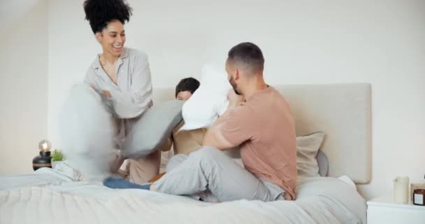 Happy, bed and family with pillow fight at their home having fun and bonding together on a weekend. Smile, playful and young boy child playing with his parents in bedroom of modern house in Canada - Footage, Video