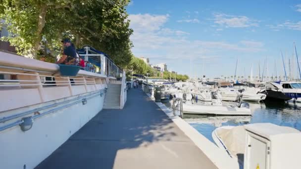 JUAN LES PINS, FRANCIE - 4. ZÁŘÍ 2023: Pěší lidé v blízkosti Port Gallice plné luxusních jachet a plachetnic - Záběry, video