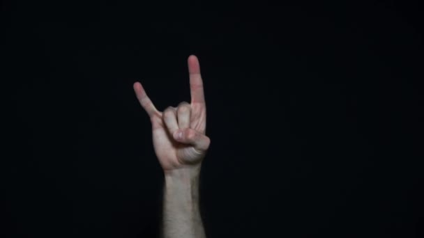 Primer plano de la mano mostrando el cartel de rock n roll sobre un fondo negro. Gestos de cuernos del diablo - Metraje, vídeo