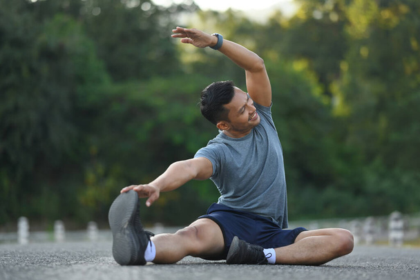Athletischer Mann, der seine Muskeln vor dem morgendlichen Laufen dehnt. Fitness, Sport und gesunder Lebensstil - Foto, Bild