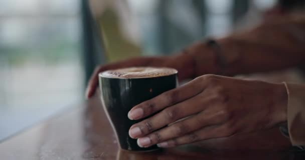 Woman, drinking and beverage while thinking in cafe with cup for calm, relax and joy. African person, hand and hold of delicious coffee, cappuccino or latte in restaurant while looking out window. - Footage, Video
