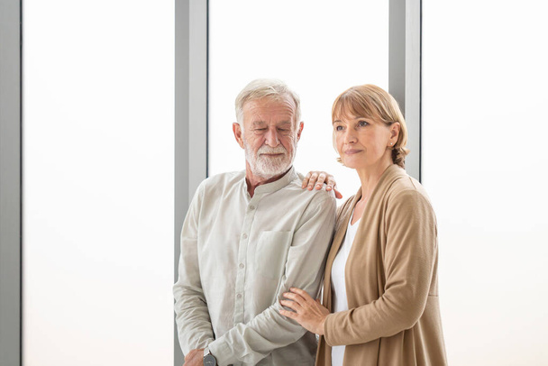 Portrait of a happy senior couple standing near the window, Joyful nice elderly couple smiling while being in a great mood, Elderly couple concepts - Foto, immagini