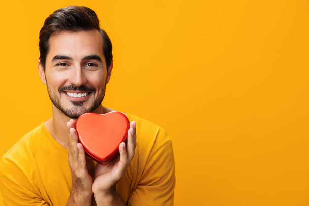 Mies hymyilevä konsepti sormi romanssi lahja romanttinen käsi muotokuva Ystävänpäivä sydän onnellinen keltainen rakkaus punainen studio laatikko symboli tausta muoto - Valokuva, kuva