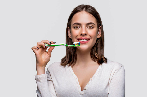 Higiene dental. Mujer joven sonriente con dientes sanos sosteniendo un cepillo de dientes. Joven hermosa chica sosteniendo un cepillo de dientes. - Foto, imagen