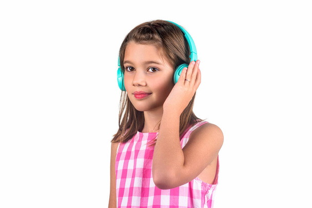Μικρό κορίτσι που ακούει μουσική με ακουστικά. Παιδί ακούει μουσική πορτοκαλί φόντο. Καλύτερες δωρεάν μουσικές εφαρμογές για την κινητή συσκευή σας. Απολαύστε τον ήχο. Χαριτωμένο μικρό με ακουστικά σε λευκό φόντο. - Φωτογραφία, εικόνα