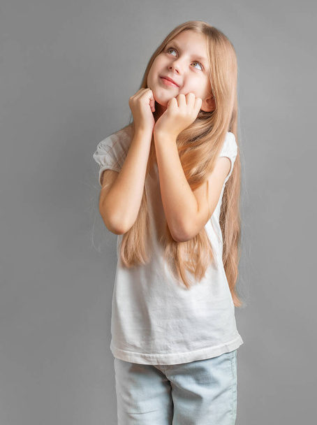 Portret pozytywnej wesołej dziewczyny słodko uśmiechniętej, dziewczyny z długimi blond włosami w białej koszulce - Zdjęcie, obraz