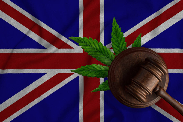 Σημαία της Μεγάλης Βρετανίας και δικαιοσύνη ξύλινο σφυρί με φύλλα κάνναβης. Παράνομη ανάπτυξη φυτών και ναρκωτικών κάνναβης - Φωτογραφία, εικόνα