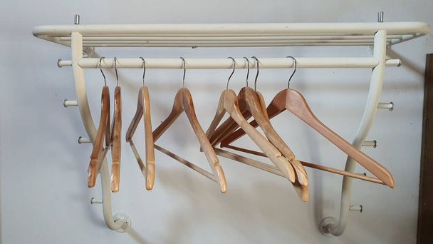 Kleiderbügel aus Holz hingen ohne Kleidungsstück an einer Schrankstange - Foto, Bild