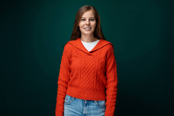 Красивая молодая женщина с каштановыми волосами в красном свитере на зеленом фоне. - Фото, изображение