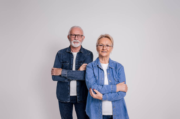Portrait of confident senior husband and wife in eyeglasses with arms crossed on white background - Photo, Image