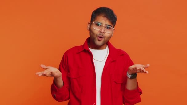 Mitä nyt? En tiedä. Vihainen intialainen mies nostaa kätensä närkästyneenä, kysyy epäonnistumisen syytä, osoittaa epäuskon ärsytystä ongelmilla. Arabian nuori kaveri eristetty oranssi studio tausta - Materiaali, video