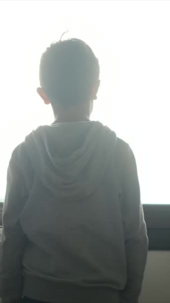 Rückansicht eines Jungen im Kapuzenpulli, der in der Stadt aus dem Fenster schaut. - Filmmaterial, Video