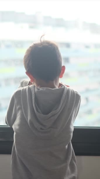 visão traseira do menino com capuz olhando pela janela na cidade. - Filmagem, Vídeo