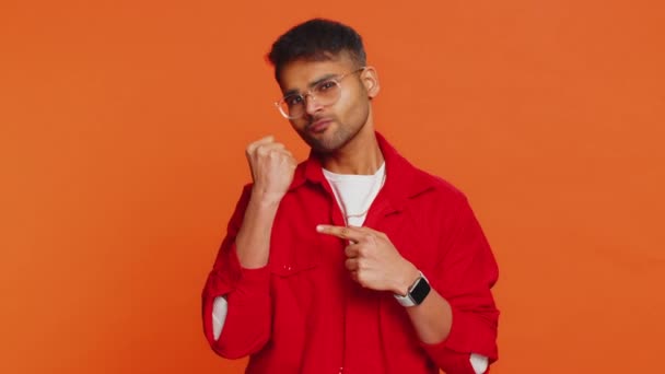 Agressieve boze Indiase jongeman probeert te vechten op camera, schudden vuist, boksen met expressie, straf, bedreigen, pesten, misbruik, gekke woede. Arabische man geïsoleerd op oranje studio achtergrond - Video
