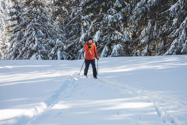 Joven esquiador de fondo adulto de 20-25 años haciendo su propia pista en la nieve profunda en el desierto durante la mañana tiempo soleado en las montañas Beskydy, República Checa. - Foto, Imagen
