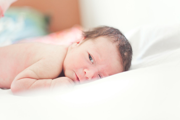 白いおむつの上に横たわる小さな生まれたばかりの赤ちゃん  - 写真・画像