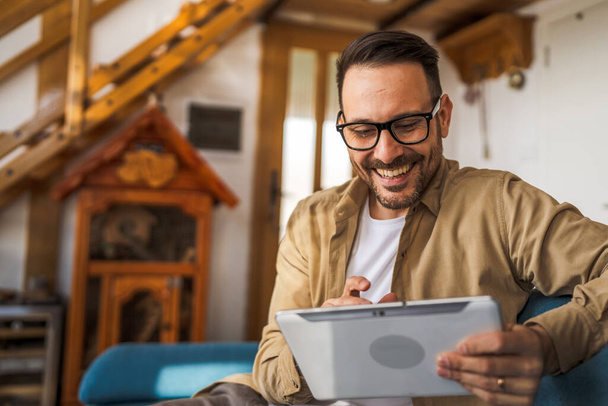 Un uomo adulto maschio caucasico tenere un lavoro tablet digitale o navigare in internet sorriso felice a casa sedersi fiducioso quotidiano mattina spazio copia persona reale - Foto, immagini