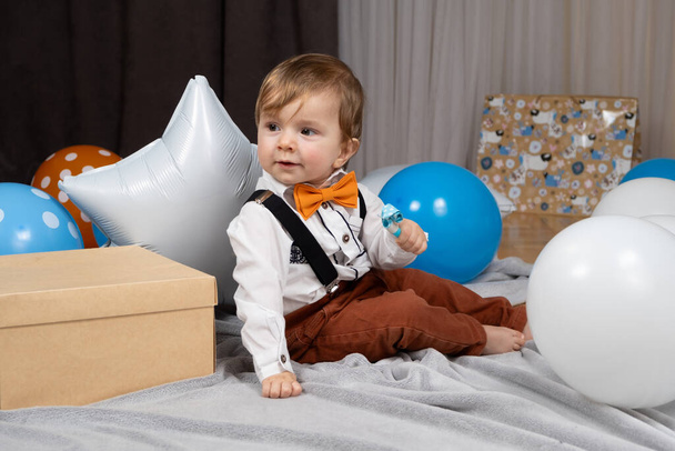 Ένα νήπιο γιορτάζει τα πρώτα του γενέθλια ανάμεσα σε μπαλόνια. - Φωτογραφία, εικόνα