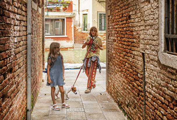 дівчата гуляють зі своїм собакою Джеком Расселом Тер'єром по вулицях Венеції вранці - Фото, зображення