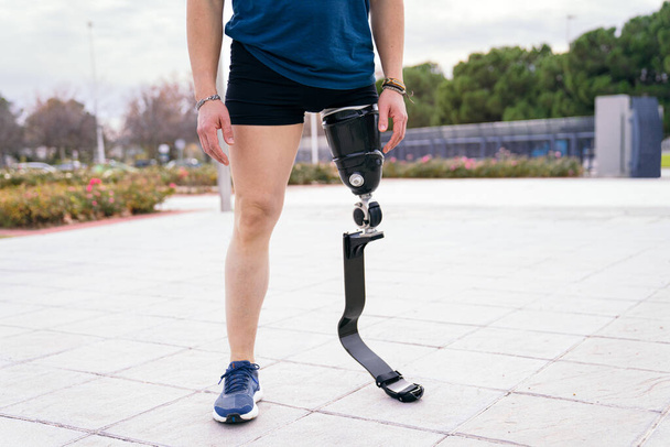 Atleta masculino irreconocible con soportes protésicos de cuchilla para correr preparados para entrenar en el parque urbano, encarnando deportes adaptativos. - Foto, Imagen