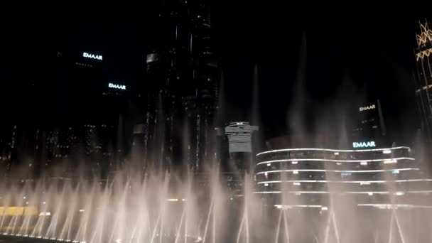 DUBAI - Emiratos Árabes Unidos, 3 de abril de 2023: Fuentes bailando en el Dubai Mall cerca de Burj Khalifa. Acción. Hermosa fuente de rendimiento por la noche en la popular zona turística  - Metraje, vídeo