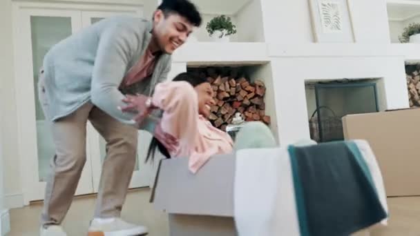 Couple, pushing box and playing in new home or celebrate moving into real estate property. A happy man and woman with fun energy and excited in their first house with mortgage, boxes and investment. - Footage, Video