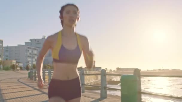 Beach, running and sports fitness of a woman runner by the sea, ocean and water with speed. Exercise, marathon training and athlete run of a person doing a health workout on concrete outdoor. - Footage, Video