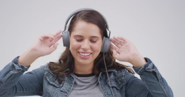 Headphones, music and face of woman in studio dance and listening to audio, radio and song playlist. Happy, chill and person relax for online streaming, subscription and sound on gray background. - Footage, Video