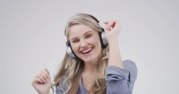 Headphones, excited and face of woman in studio dance and listening to audio, radio and song playlist. Happy, chill and portrait of person for online streaming, music and sound on gray background. - Footage, Video