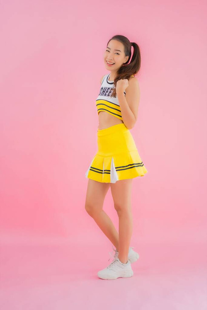 Portret mooie jonge aziatische vrouw cheerleader op roze geïsoleerde achtergrond - Foto, afbeelding