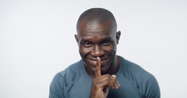 African man, studio and finger on lips with smile on face for training secret, fitness or health by white background. Personal trainer, sign language or icon for silence, promotion or deal for gym. - Footage, Video