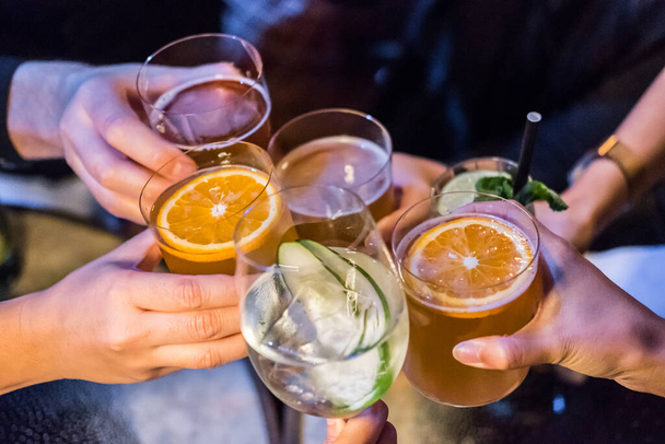 Un gruppo di persone brinda con bicchieri di cocktail sul tavolo - Foto, immagini