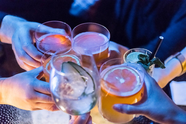 Ryhmä ihmisiä nostaa maljan lasillinen cocktaileja pöydällä. - Valokuva, kuva