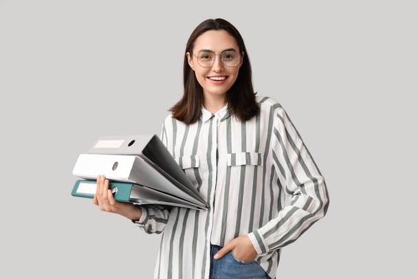 Junge Geschäftsfrau mit Aktenmappen auf hellem Hintergrund - Foto, Bild