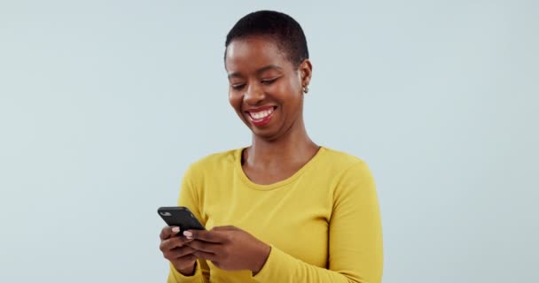 Mujer, sonríe o escribe en el teléfono inteligente en el estudio, desplázate por las redes sociales o lee una divertida notificación de contacto sobre fondo blanco. Modelo africano feliz descarga aplicación digital, juegos móviles o meme de búsqueda. - Metraje, vídeo