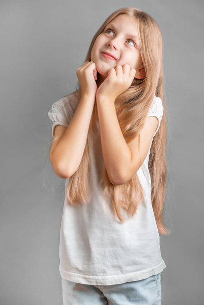 Portrait de fille positive gaie et joliment souriante, fille aux longs cheveux blonds en t-shirt blanc - Photo, image