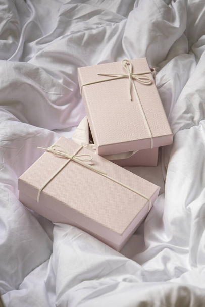 Δύο ανοιχτόχρωμα ροζ κουτιά δώρου σε ένα τσαλακωμένο λευκό πανί. Πάνω άποψη, επίπεδη lay. - Φωτογραφία, εικόνα