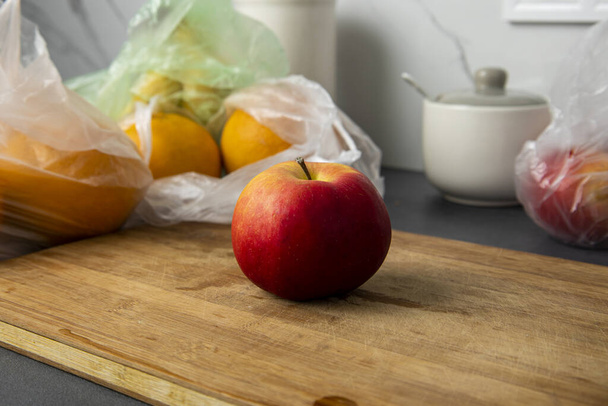 Fresh fruits in a transparent plastic bag lie in the kitchen. - Photo, image