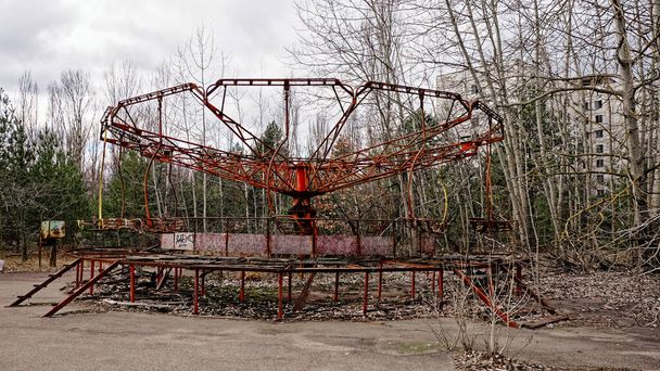 An old, neglected merry-go-round with peeling paint amidst bare trees. - Photo, Image